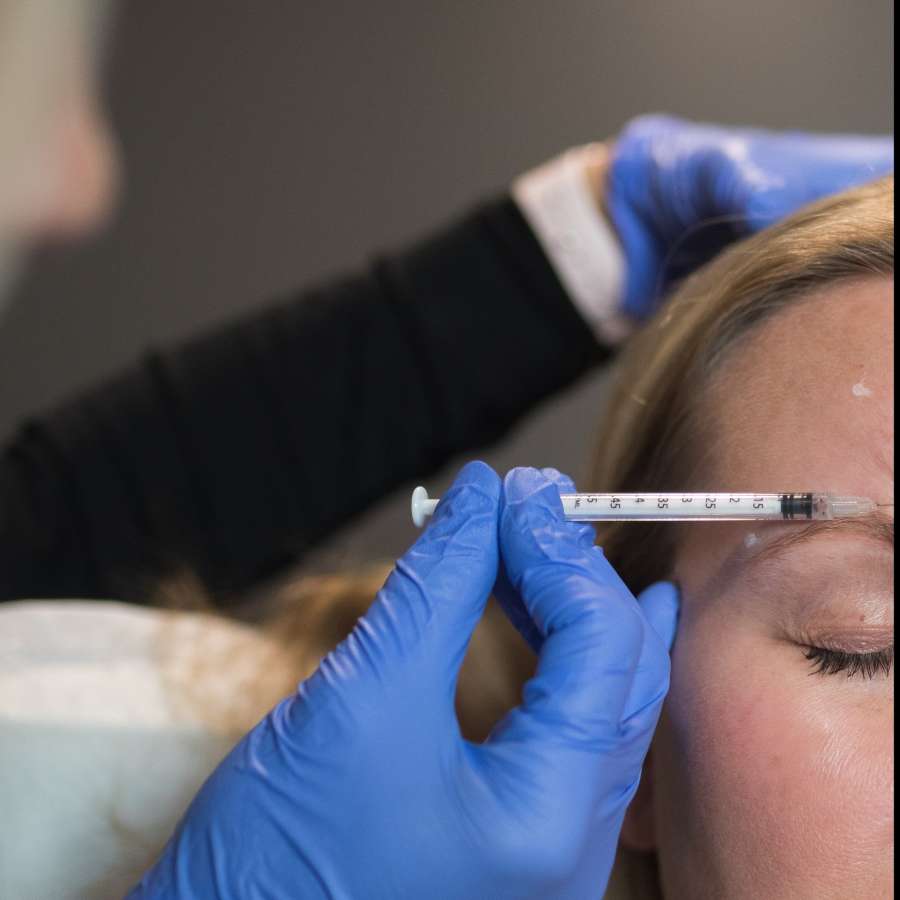 Image of a woman receiving a Botox injection in her cheek.